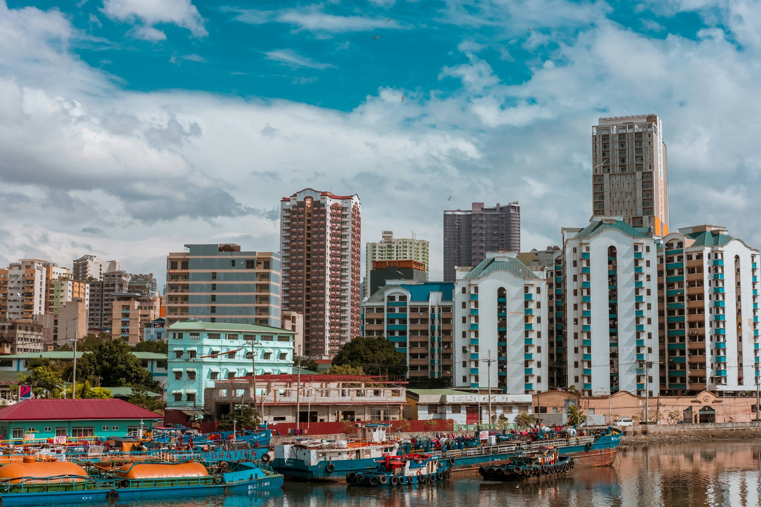 City skyline with tall buildings and a waterfront docked boats.