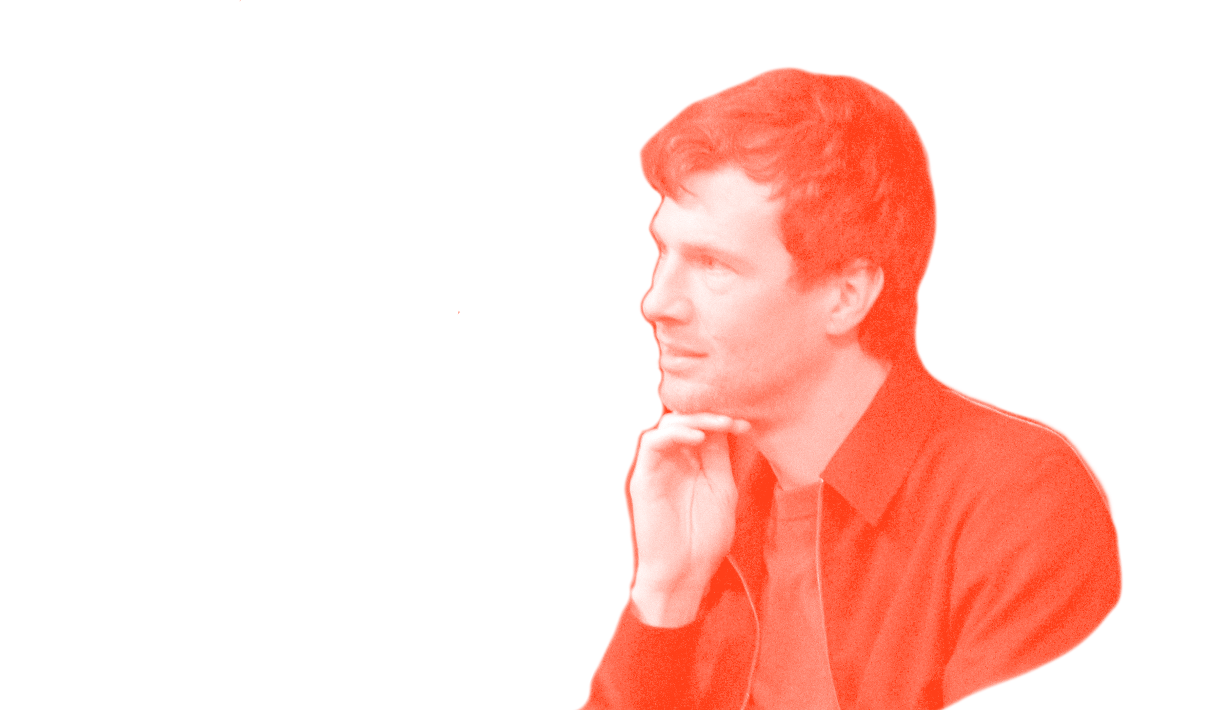 A young man with red hair, wearing a black shirt, resting his chin on his hand and looking to the left with a thoughtful expression.