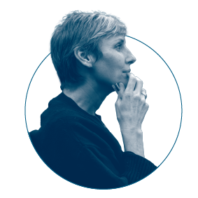 Side profile of a woman with short hair, holding a pen near her lips, appearing contemplative.