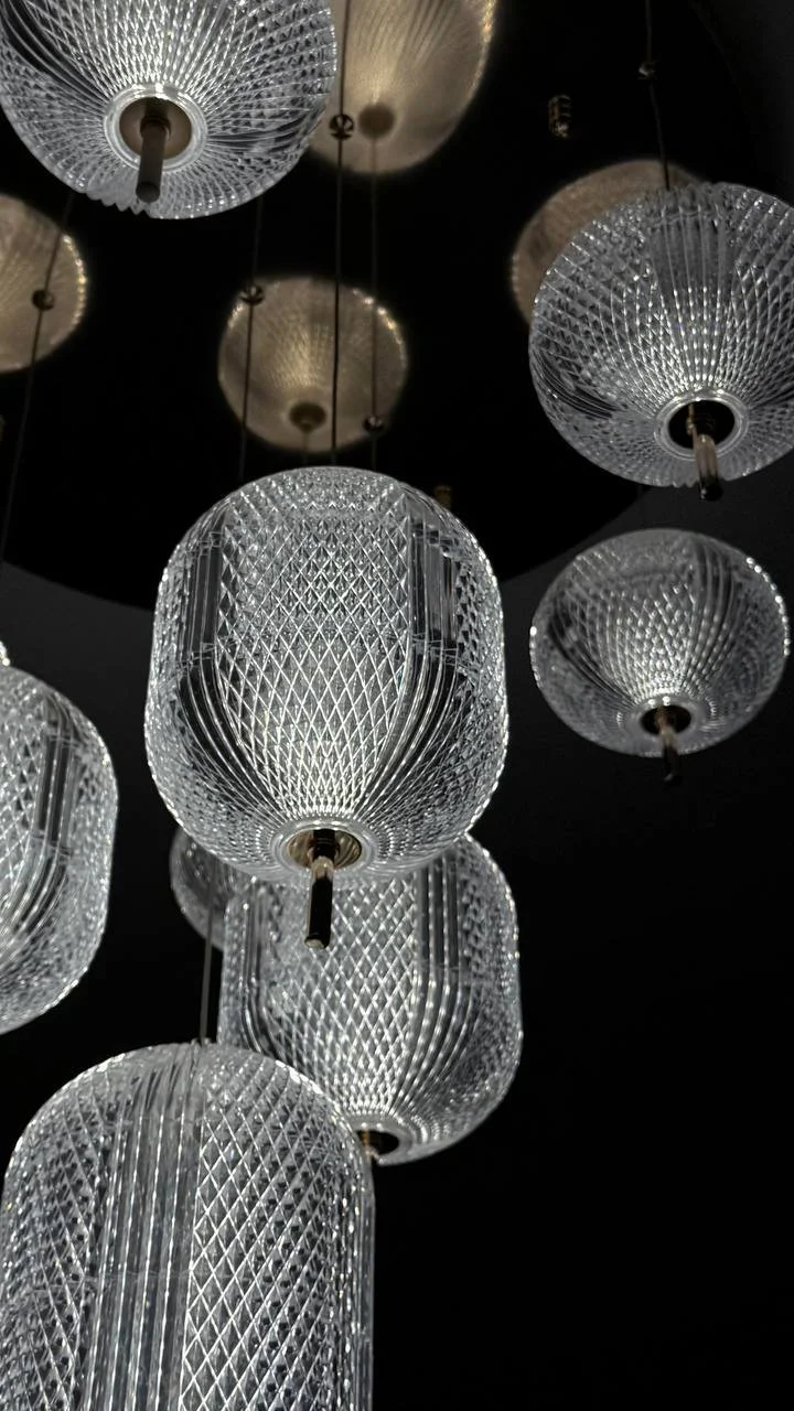 Nuo lubų kabantys dekoratyviniai stikliniai šviestuvai tamsiame fone.