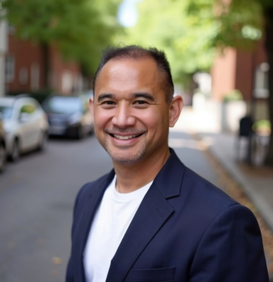 Person with curly hair standing in front of an airplane window, looking outside as rain hits the window. The photo is in black and white.