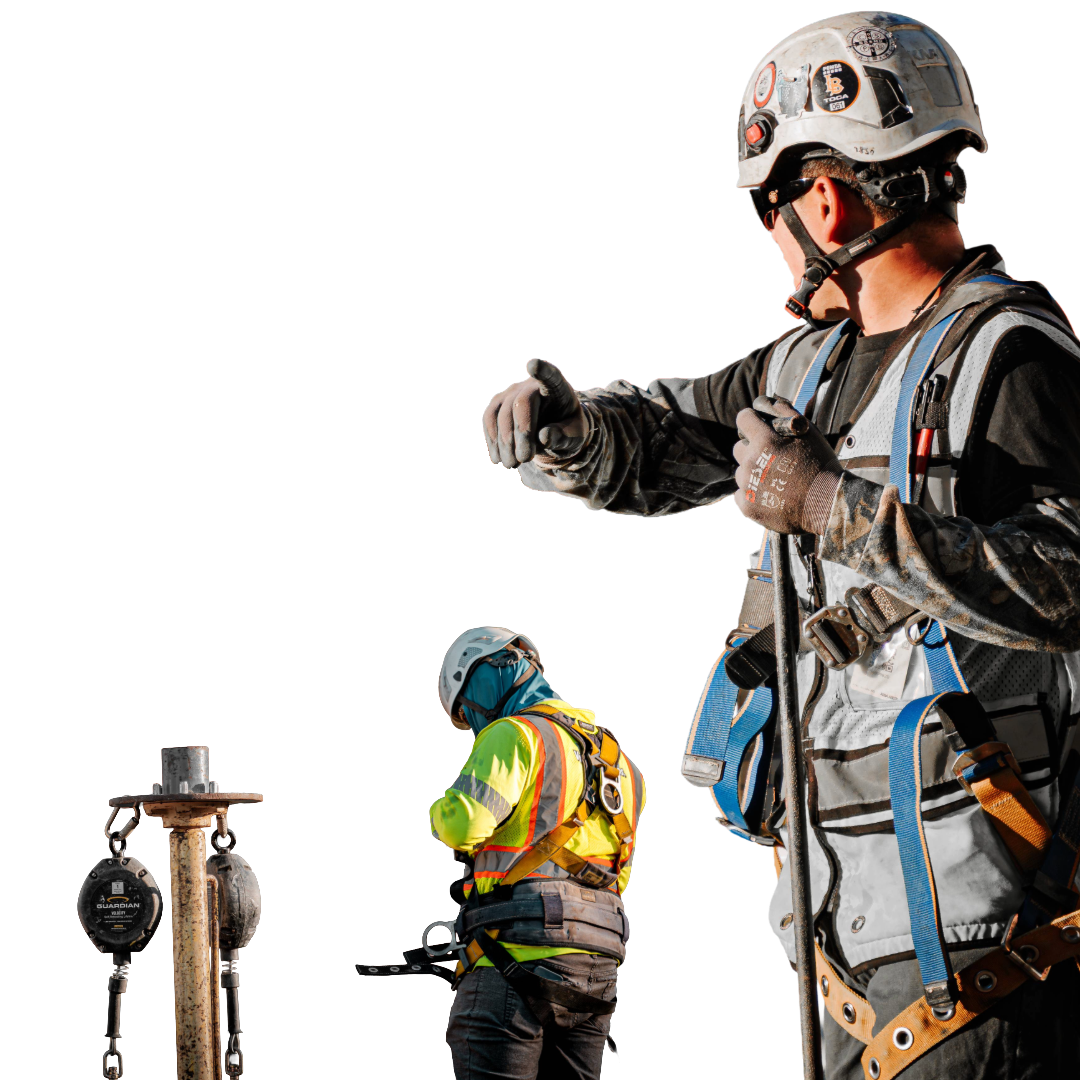 Two construction workers wearing safety gear, helmets, and harnesses working with equipment on a construction site.