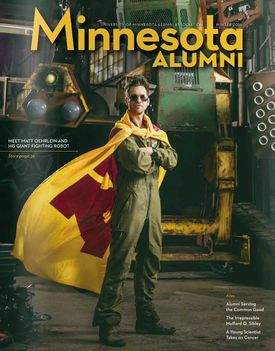 Magazine cover featuring a man in military jumpsuit and sunglasses, crossing his arms in front of vintage machinery, draped in a yellow and red flag, with the title 'Minnesota ALUMNI' at the top.