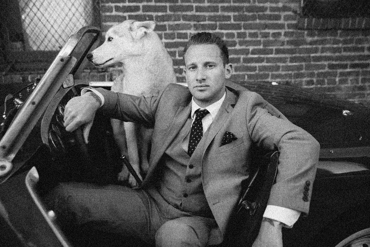 Black and white editorial portrait of a suited man in a vintage convertible with a white dog, San Francisco – Marc Olivier Le Blanc Photography
