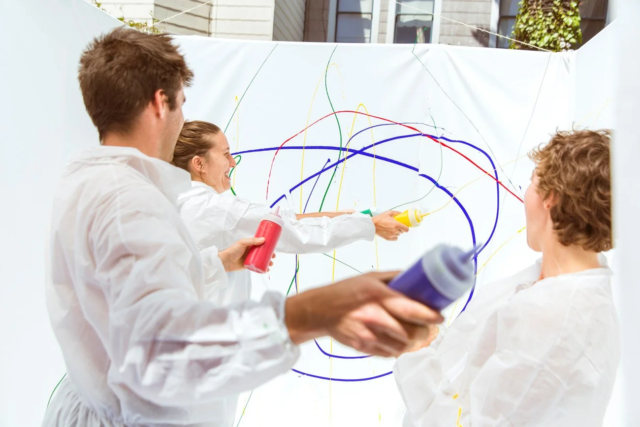 Lifestyle photo of three people in white coats throwing colorful paint at a canvas outdoors, San Francisco – Marc Olivier Le Blanc Photography