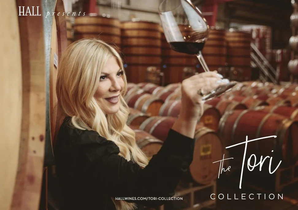 Advertising campaign photo for Hall Wines Tori Spelling Collection featuring a woman holding a wine glass in a Napa Valley barrel room – Marc Olivier Le Blanc Photography