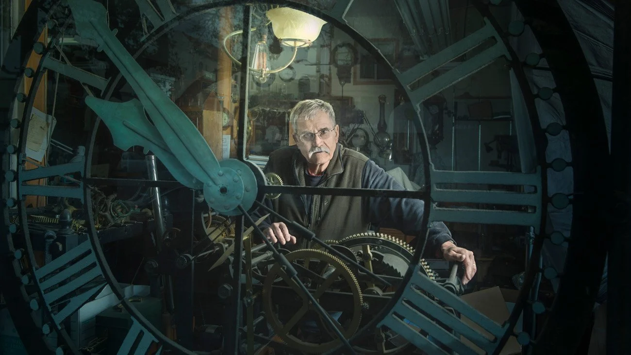 Editorial portrait of a clockmaker framed inside a large antique clock mechanism, San Francisco – Marc Olivier Le Blanc Photography