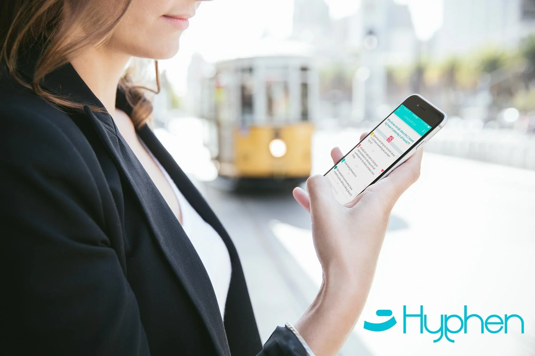 Advertising lifestyle photo of a professional woman checking the Hyphen app on her smartphone outdoors with a San Francisco cable car in the background – Marc Olivier Le Blanc Photography