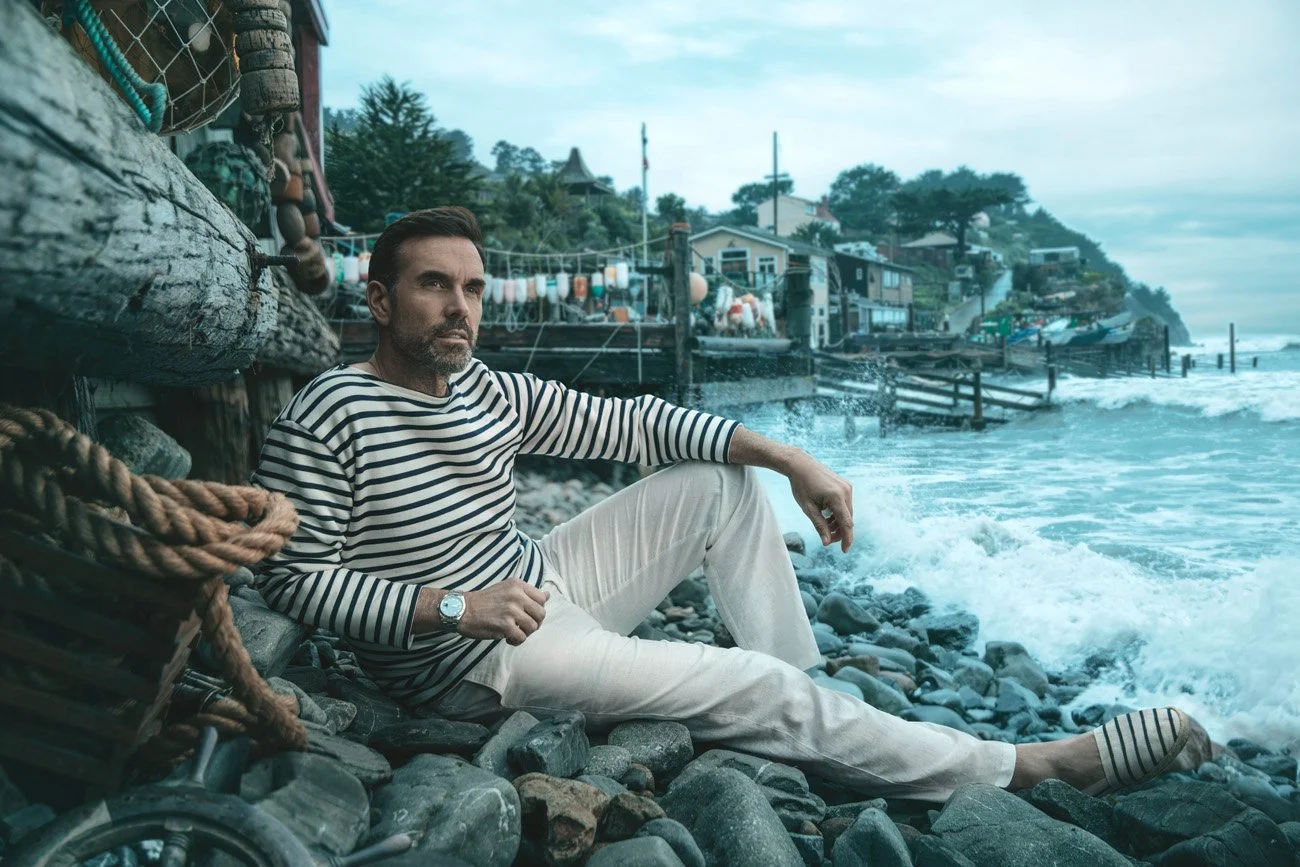 Cinematic advertising portrait of a man in a striped nautical top seated on a rocky Northern California coastline – Marc Olivier Le Blanc Photography