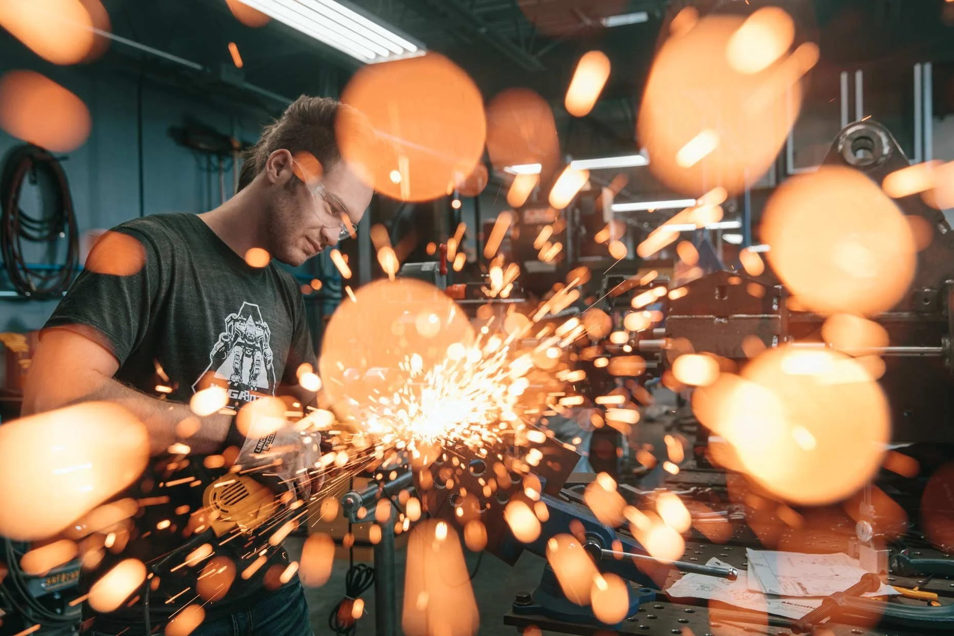 Man welding with sparks flying in a workshop or industrial setting.