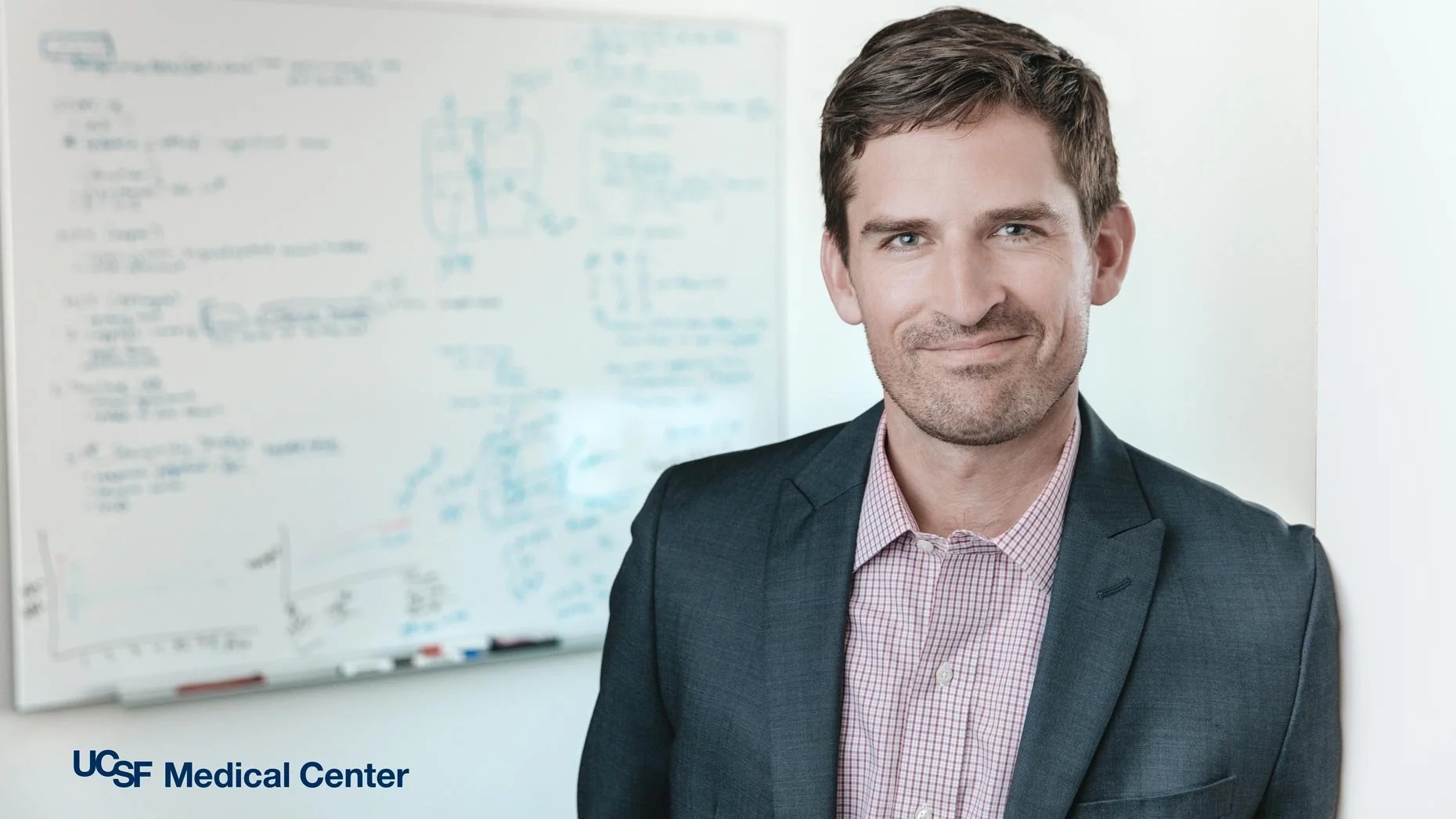 Advertising portrait of a UCSF Medical Center doctor smiling in front of a whiteboard, San Francisco – Marc Olivier Le Blanc Photography
