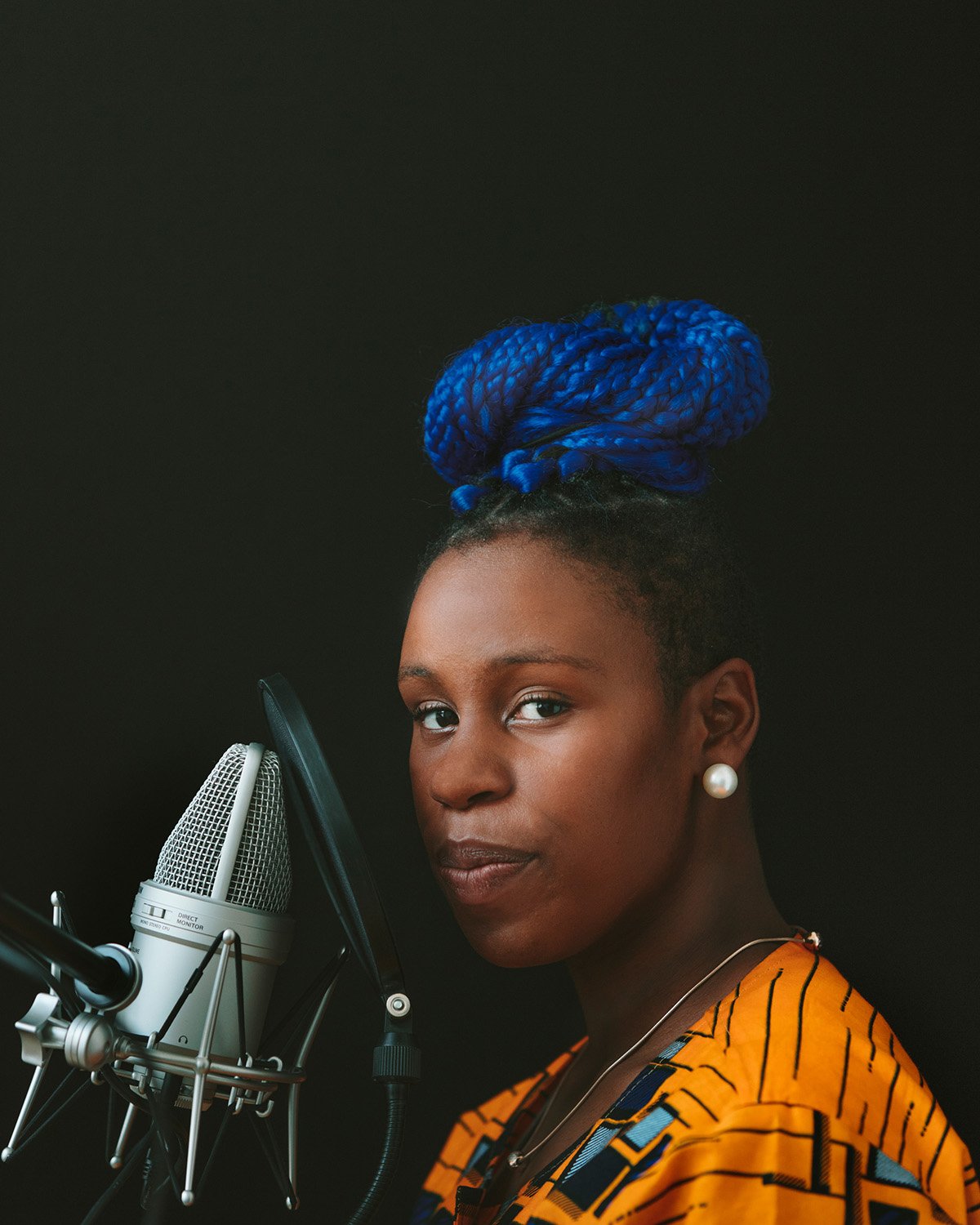 Editorial studio portrait of a woman with vibrant blue braided hair at a condenser microphone, San Francisco – Marc Olivier Le Blanc Photography