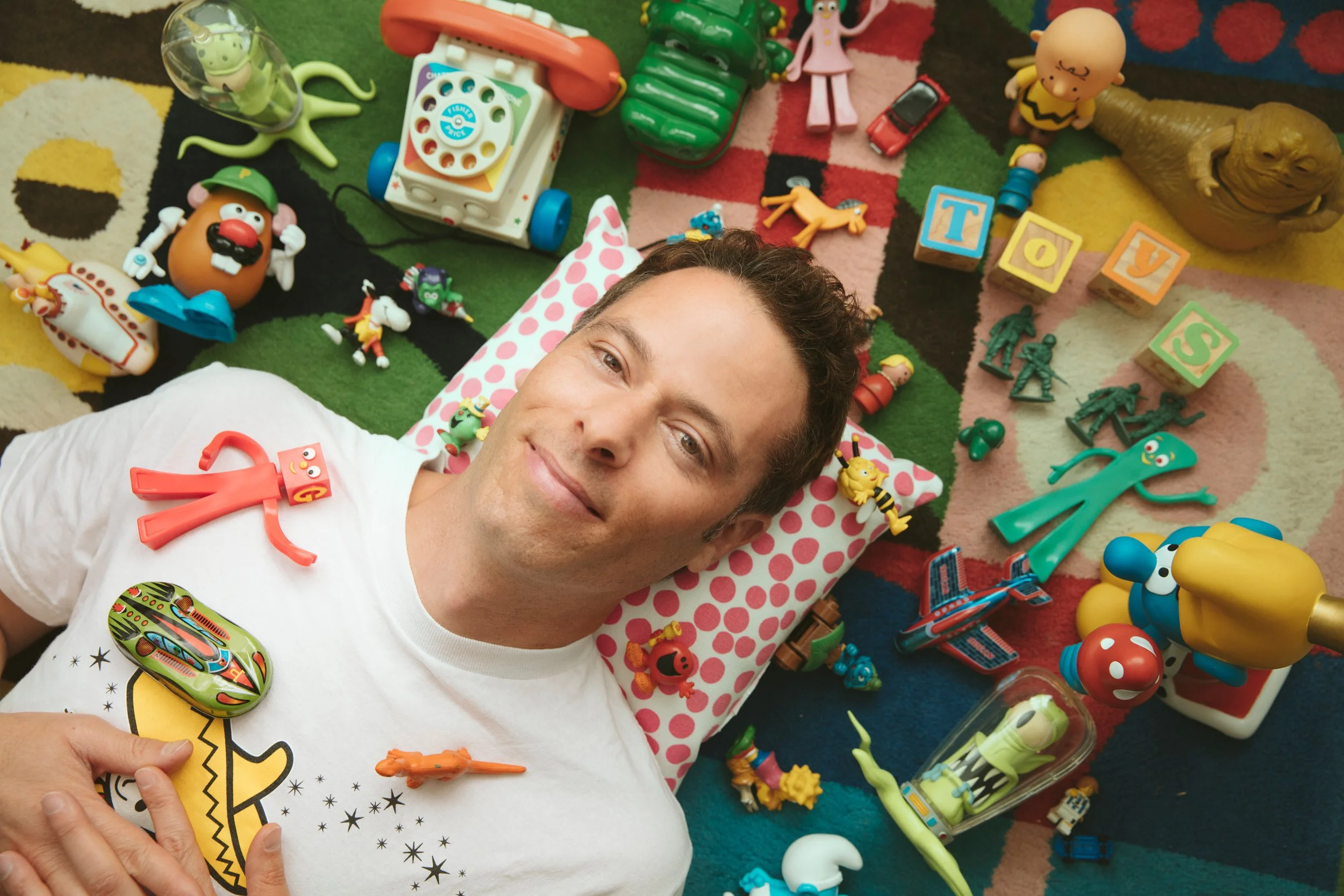 Playful editorial overhead portrait of a man surrounded by colorful vintage toys, San Francisco – Marc Olivier Le Blanc Photography