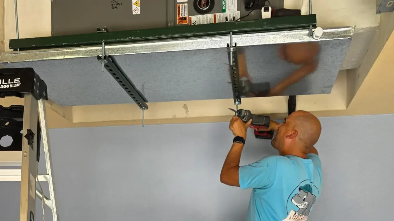 An Affordable Air Technician working on an Air Conditioner above his head.