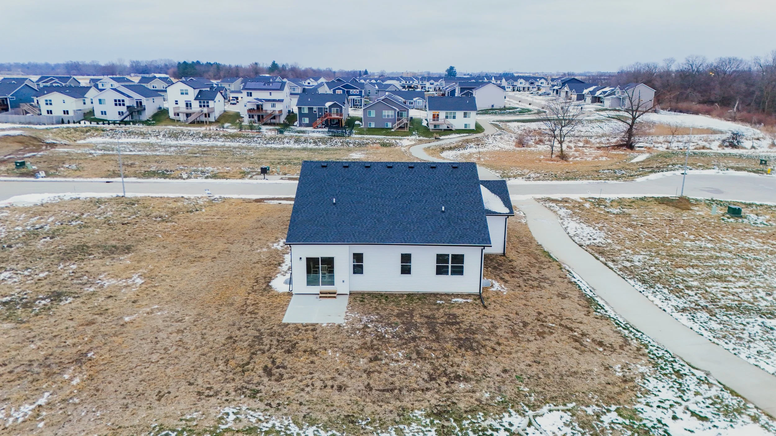 A residential house in an area still being developed in Des Moines, IA. The house is photographed with a drone, highlighting the property and its surroundings.