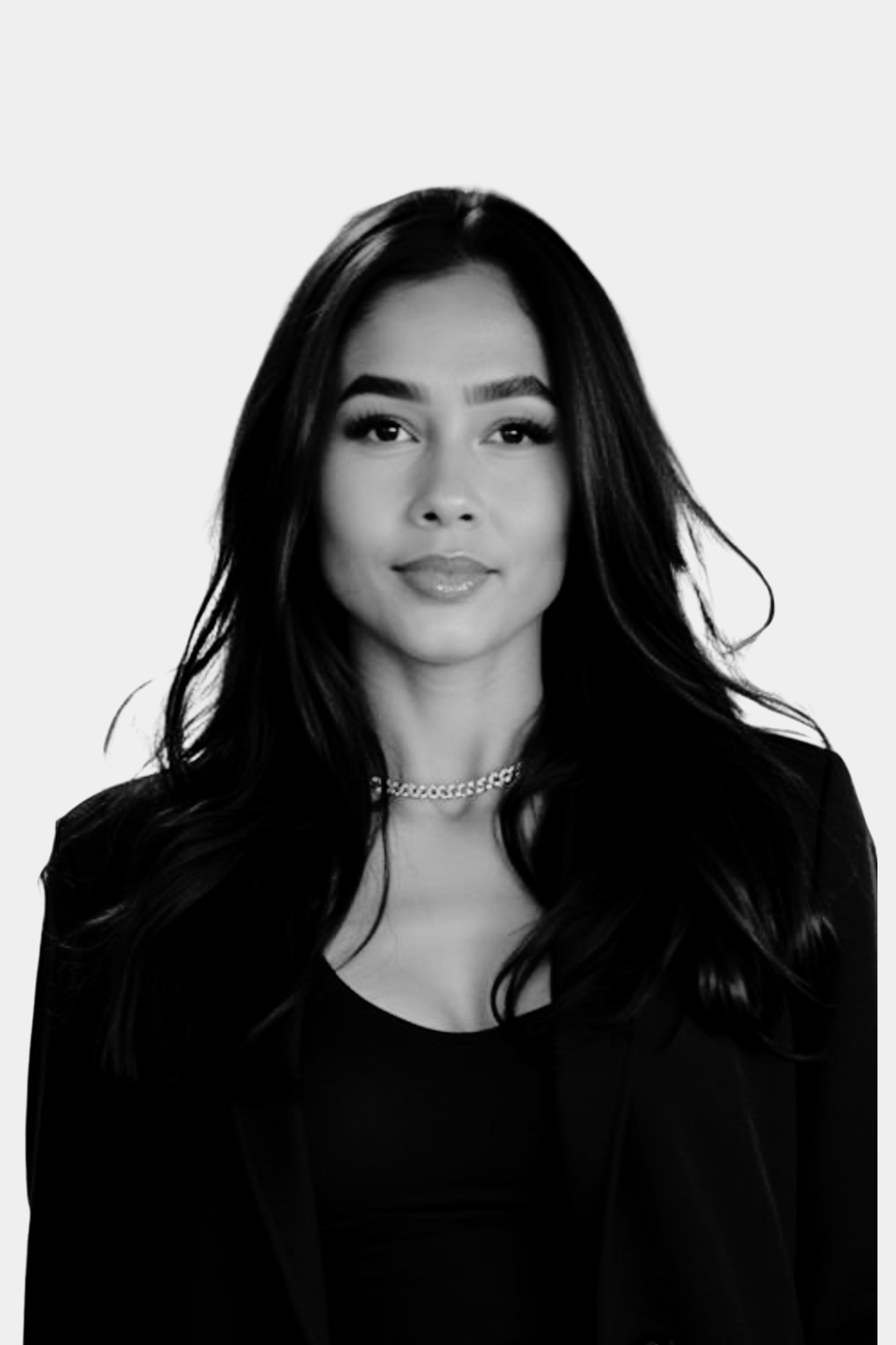 A black-and-white portrait of a woman with long, dark hair, wearing a black top and a chain necklace, against a light background.