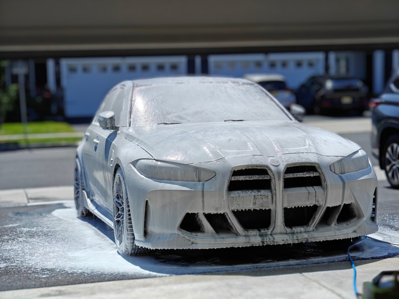 A BMW g80 being detailed covered in soap suds.