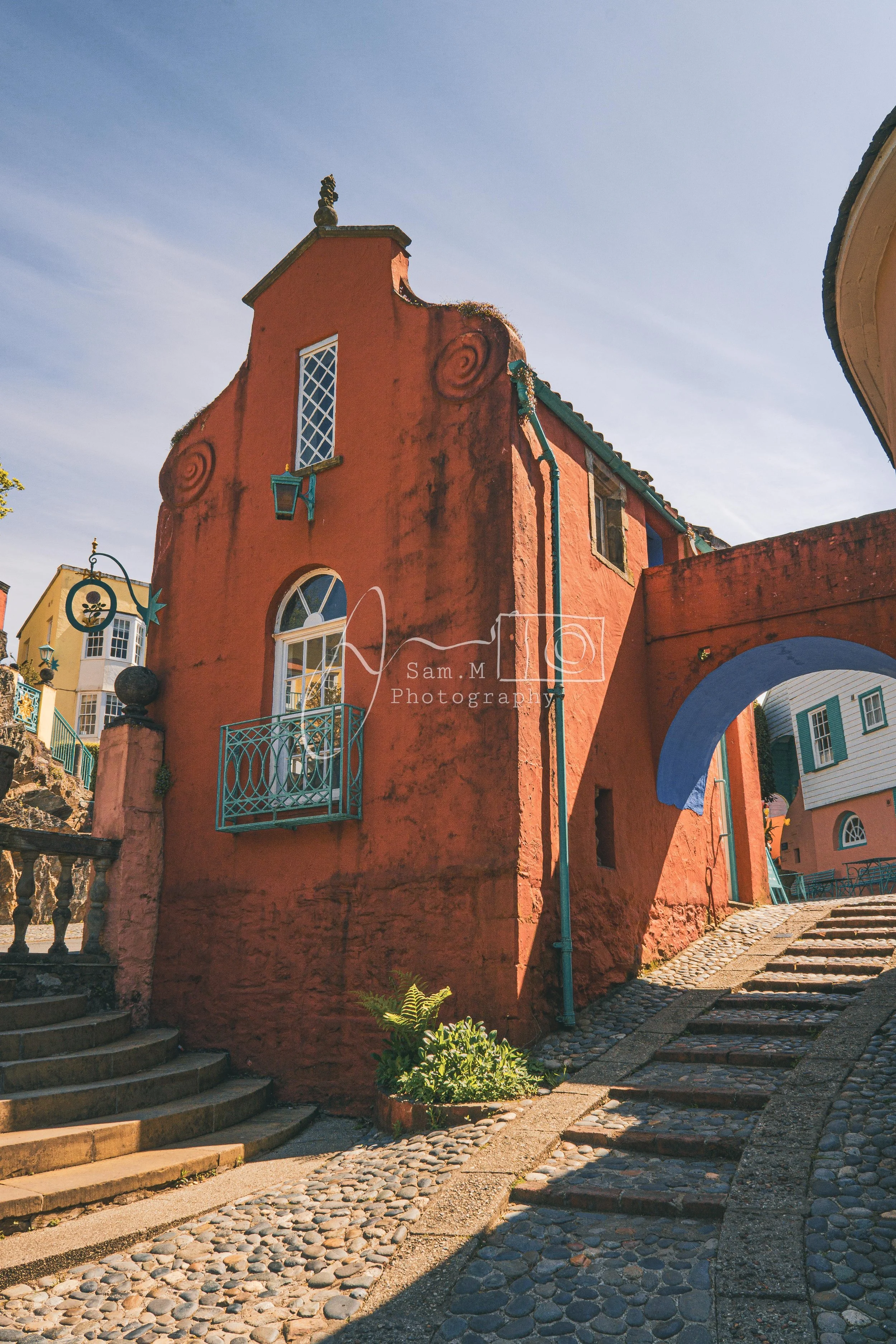 Colorful European-style street scene with pink and blue buildings, cobblestone paths, and decorative architecture.