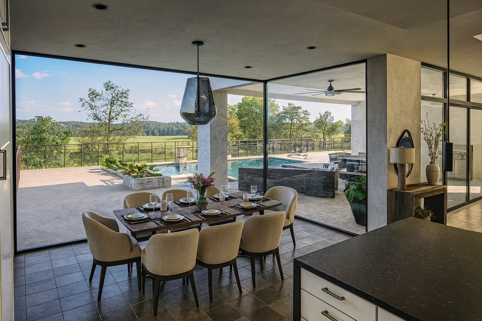Dining area with a wooden table set with plates, glasses, and a floral centerpiece, surrounded by beige chairs, overlooking an outdoor pool and scenic landscape through large glass windows.