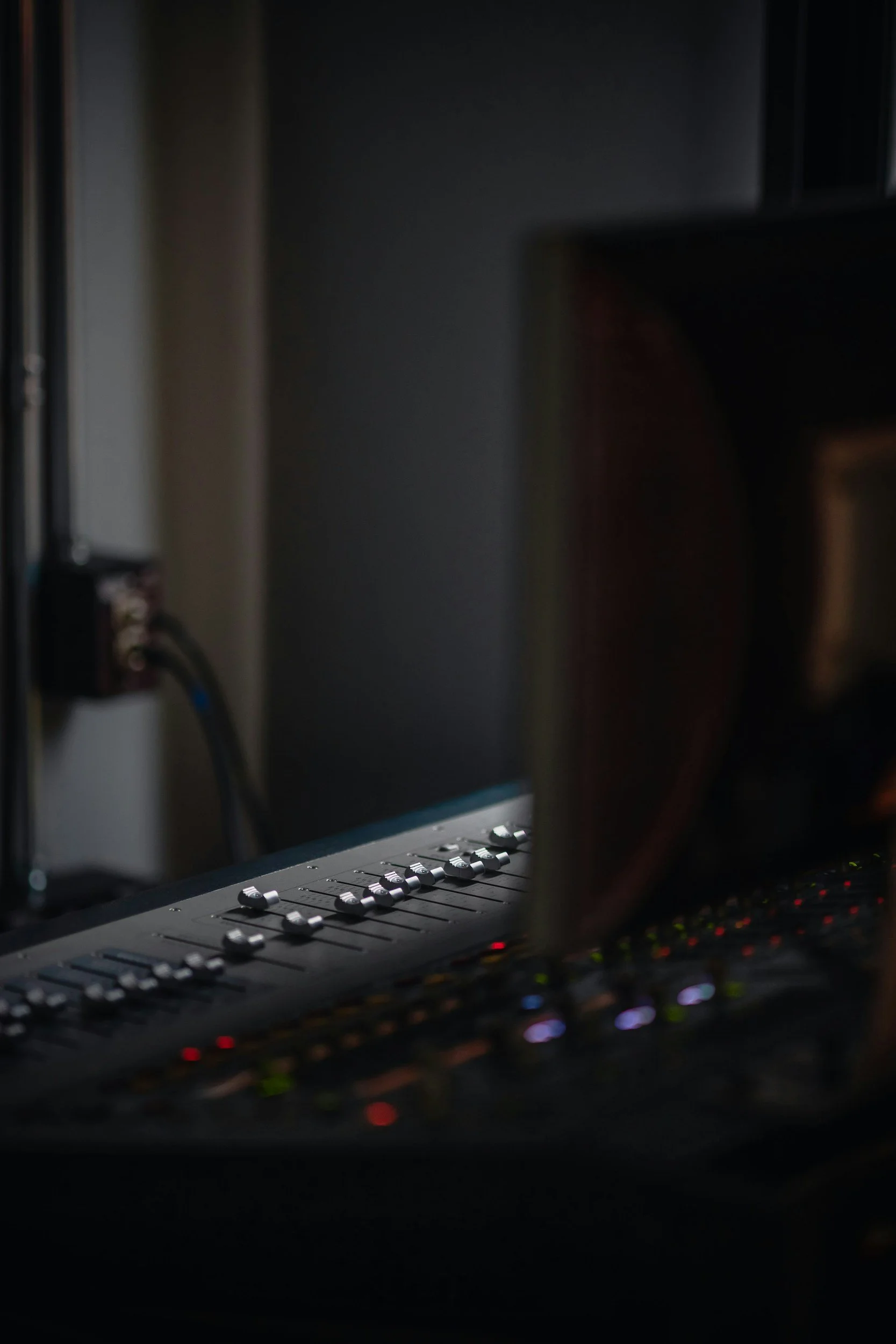 A professional audio mixing console with illuminated controls in a dimly lit room.