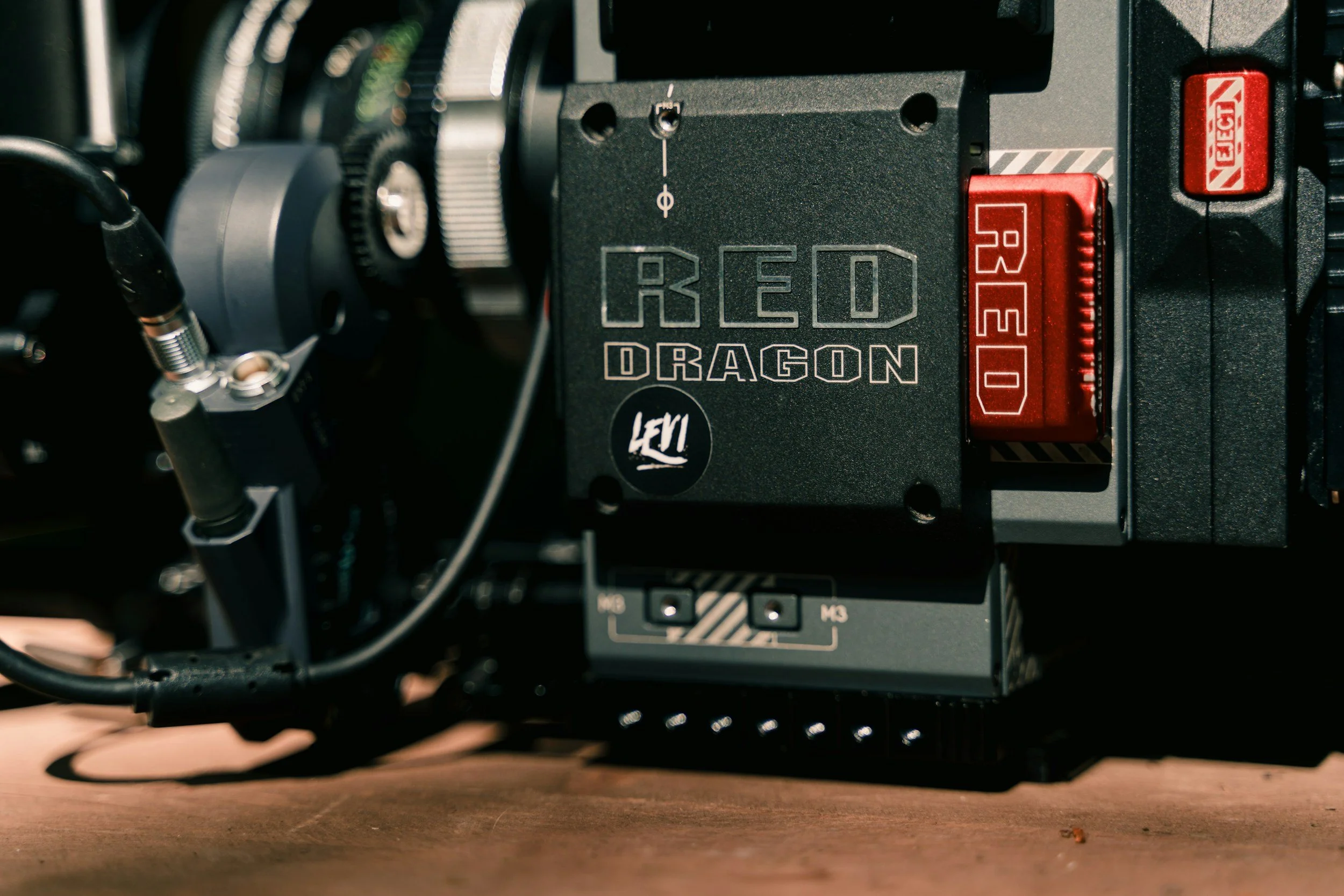 Close-up of a professional cinema camera with Hello Kitty stickers and various control buttons.