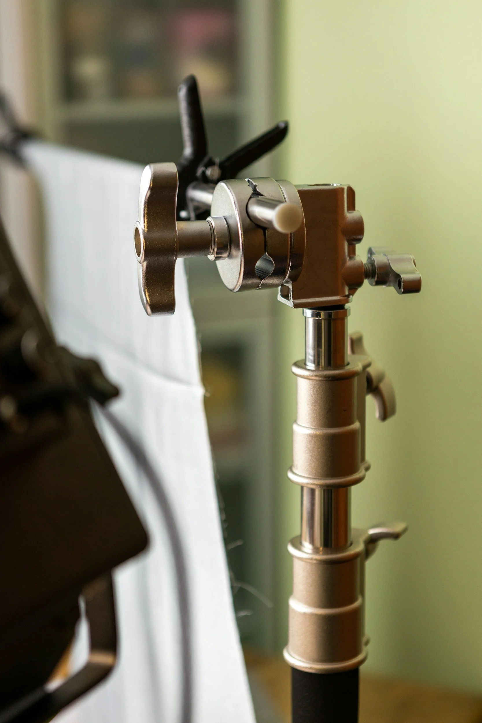 Close-up of medical or dental equipment with metallic components and a brown plastic part, set against a blurred background with a greenish wall.