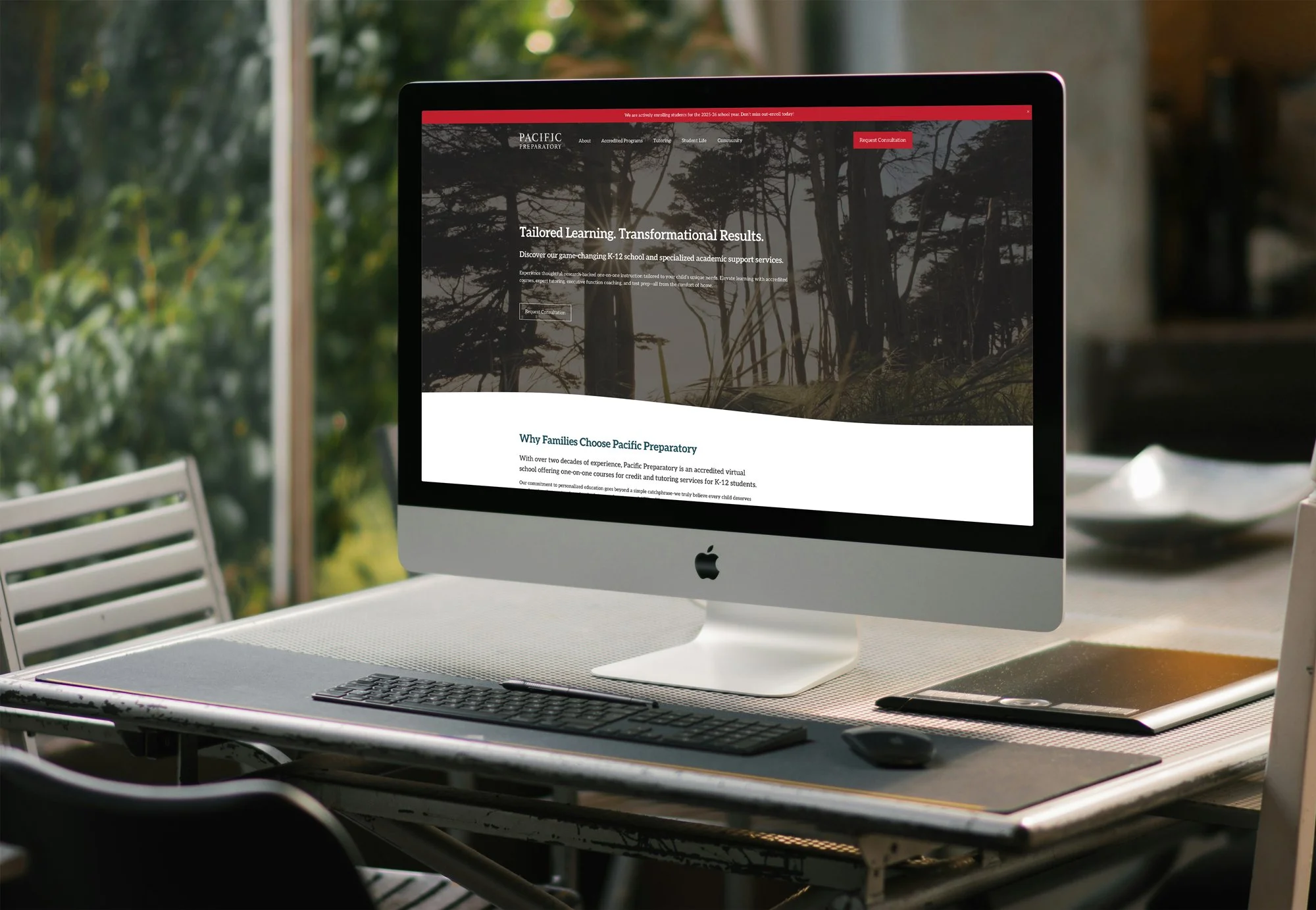 Desktop computer on a table outdoors displaying a website for Pacific Preparatory, a virtual school for K-12 education.