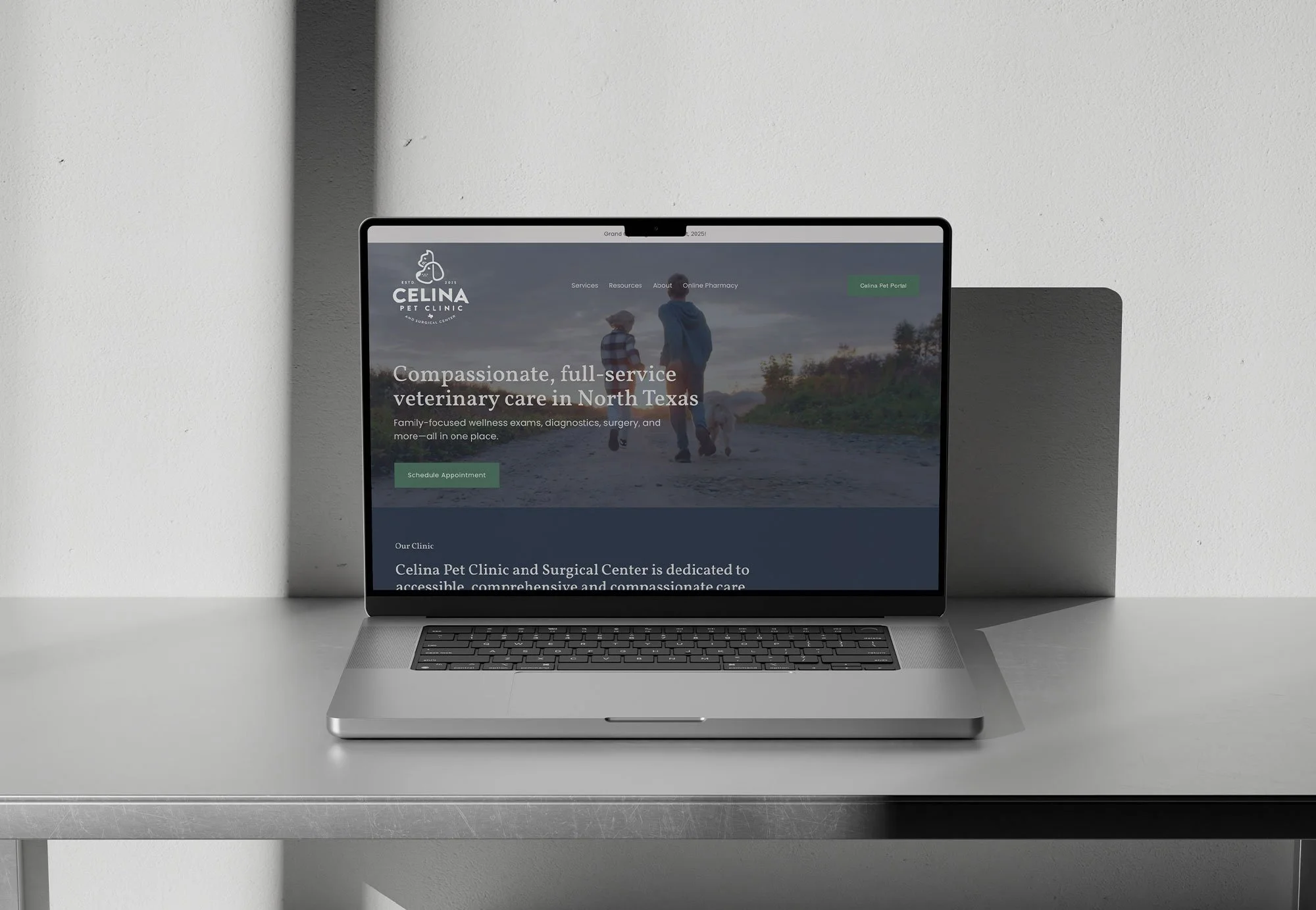 Open laptop on a minimalist gray desk displaying the homepage of 'Celina Pet Clinic and Surgical Center' website with a background image of a person walking with a child and a dog, overcast sky.