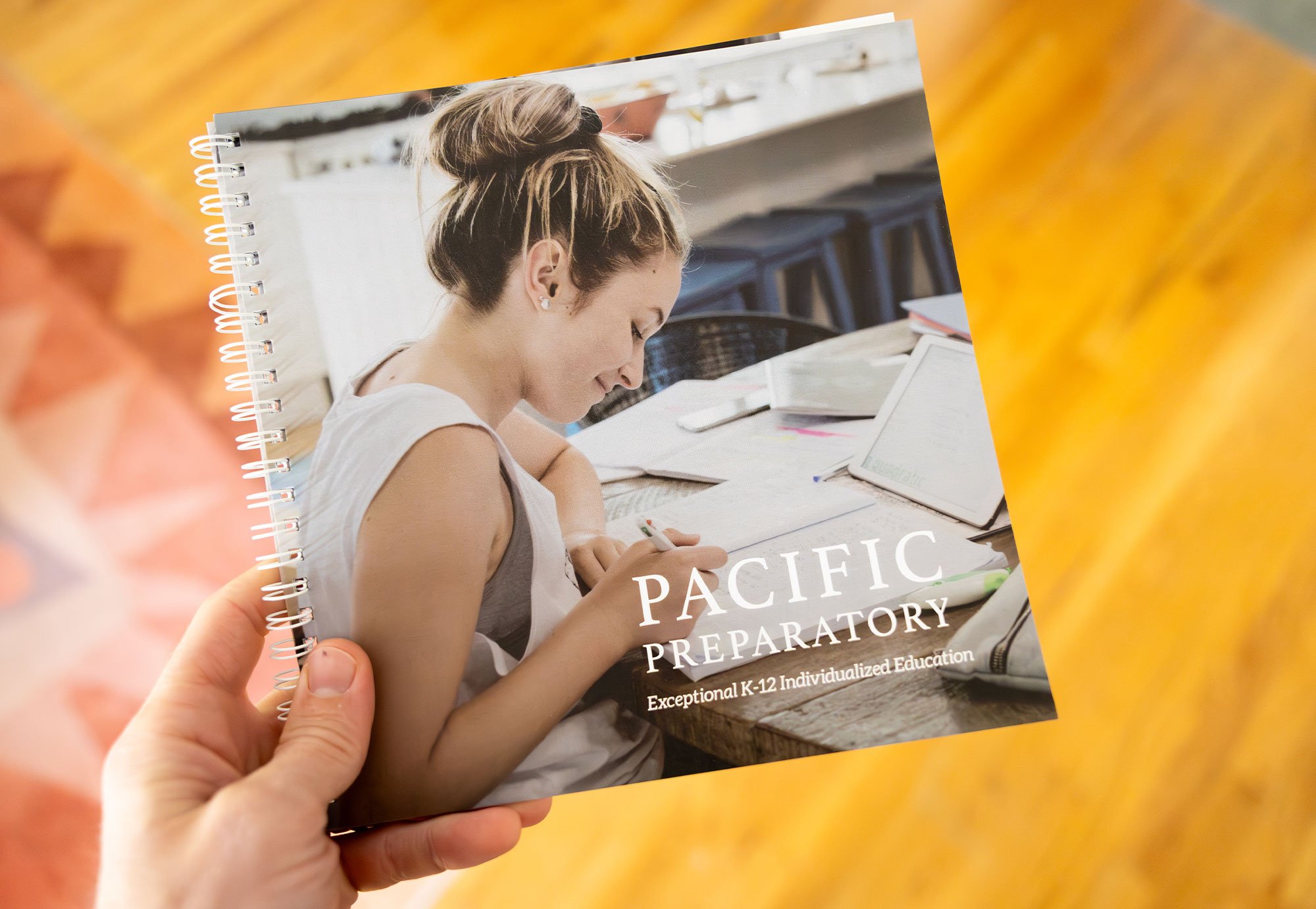 Cover of a spiral-bound notebook with a photo of a young woman writing at a table, titled 'PACIFIC PREPARATORY: Exceptional K-12 Individualized Education'.