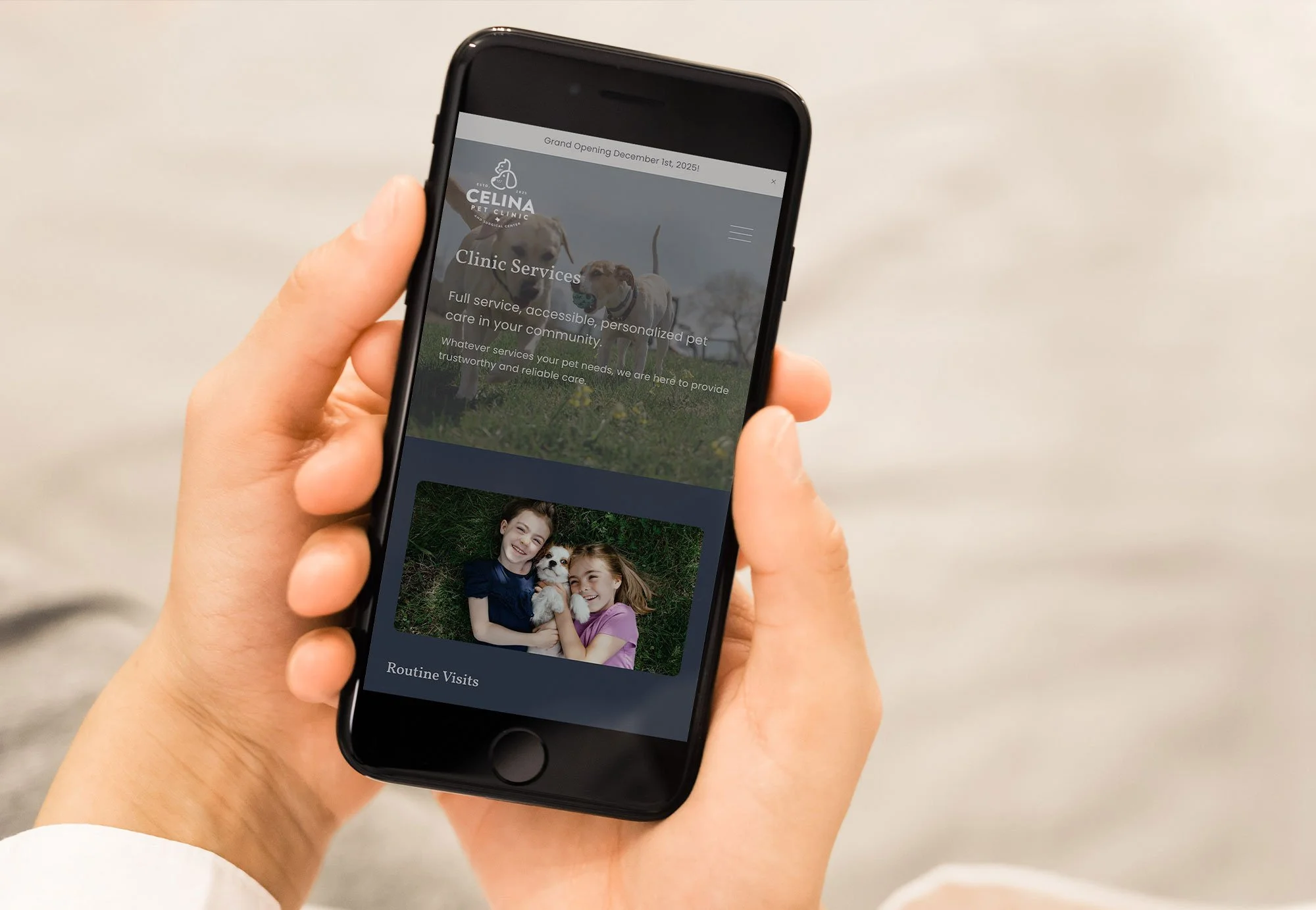 Person holding a black smartphone displaying a pet clinic website with an image of two girls holding a small dog, and information about clinic services.
