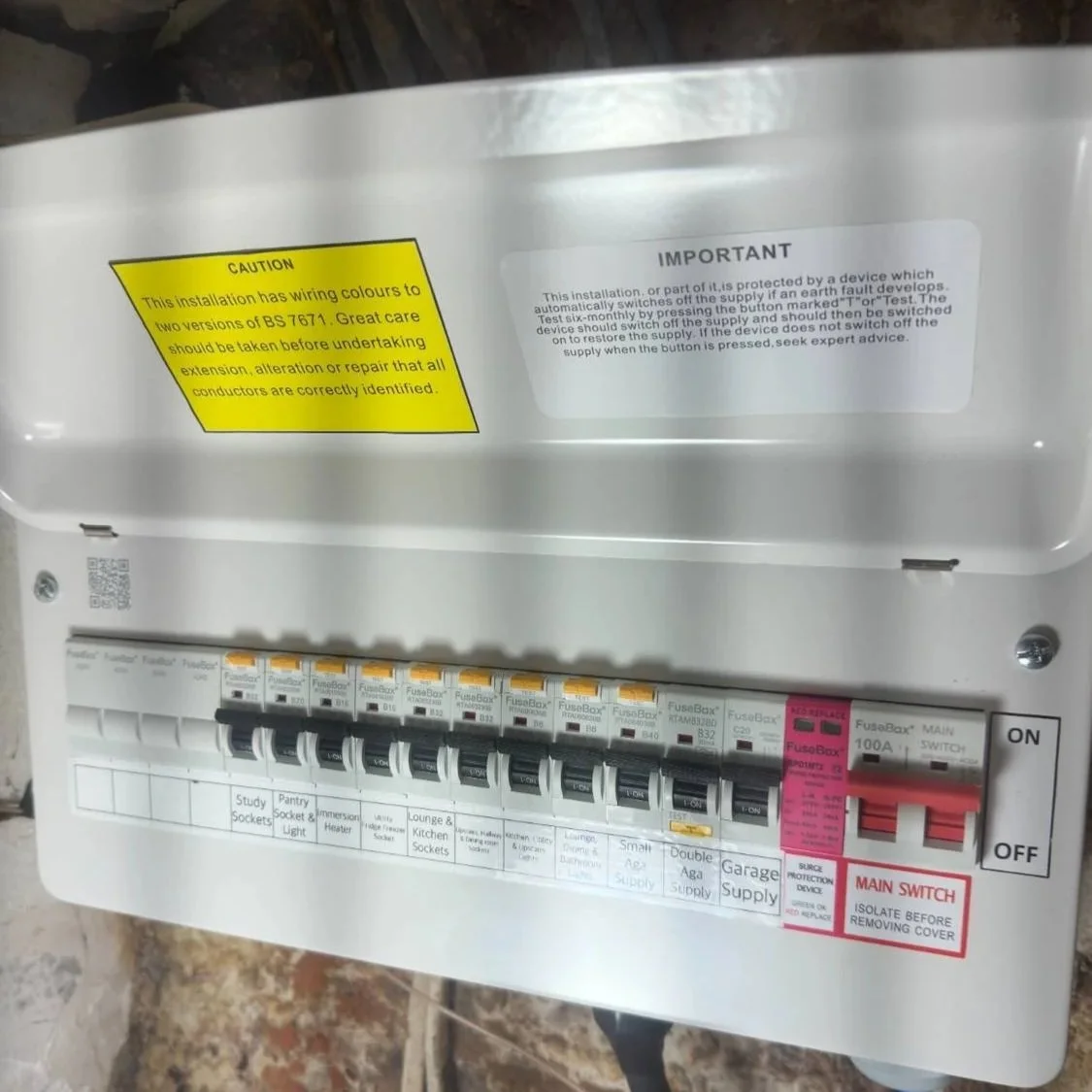 An electrical fuse box with multiple labeled circuit breakers and switches, including a main switch, warning stickers, and instruction labels.