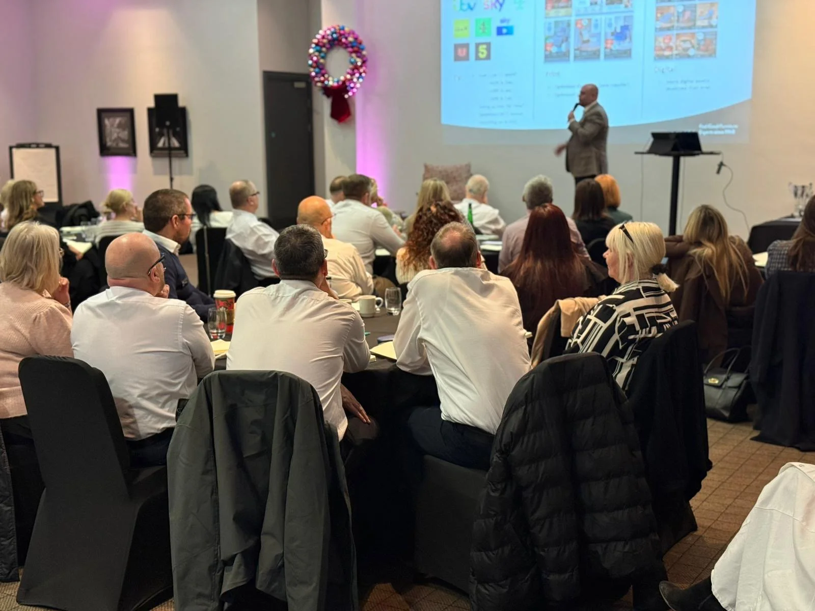 Speakers at round tables captivated by keynote speaker on small stage