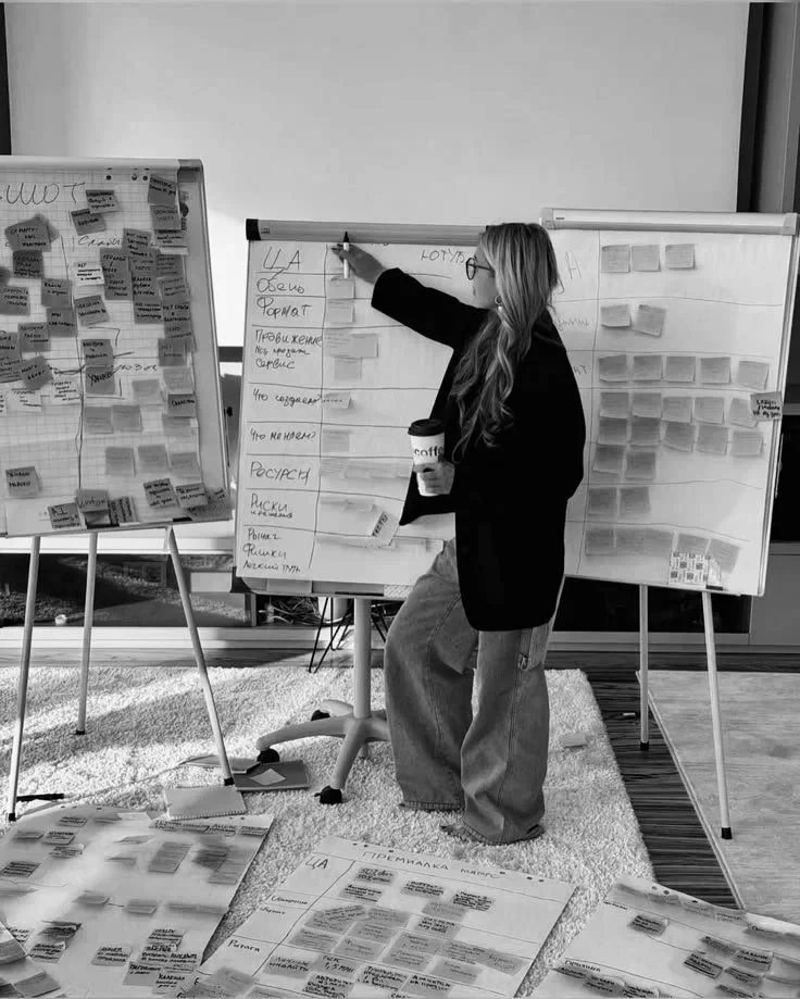 Consultant writing on a whiteboard filled with notes—systems design and strategic planning for impact work.