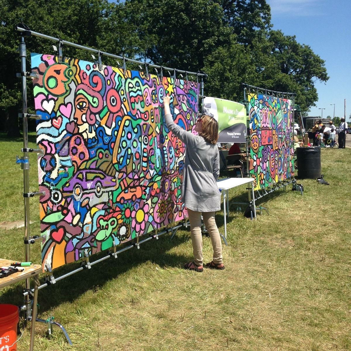 Artist painting a colorful mural at an outdoor event—public art and place-based impact.