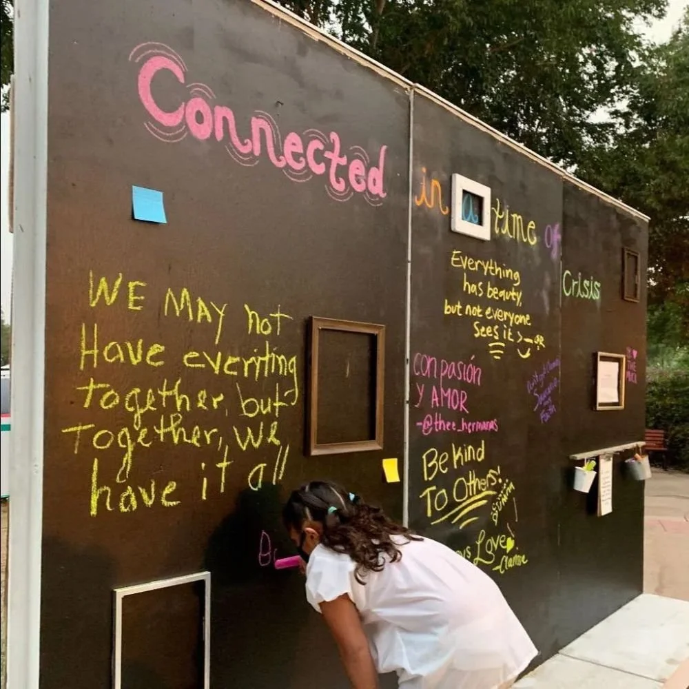 Young person writing on a chalkboard wall—community connection and creative expression.