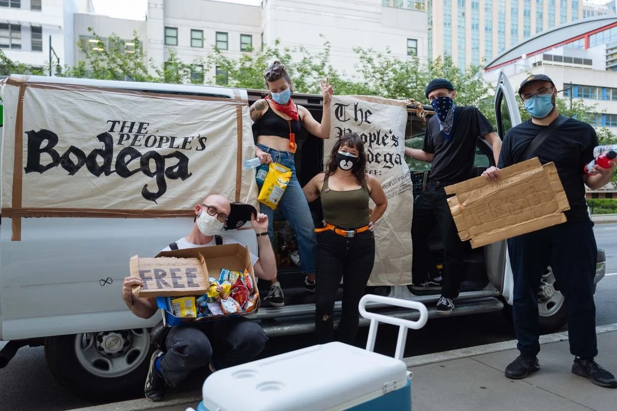 Grassroots organizing scene with signs and supplies—community power, mutual aid, and civic participation.