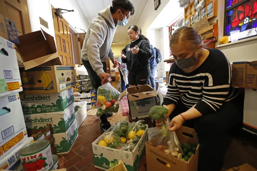 Volunteers packing fresh produce into boxes—food security and community care.