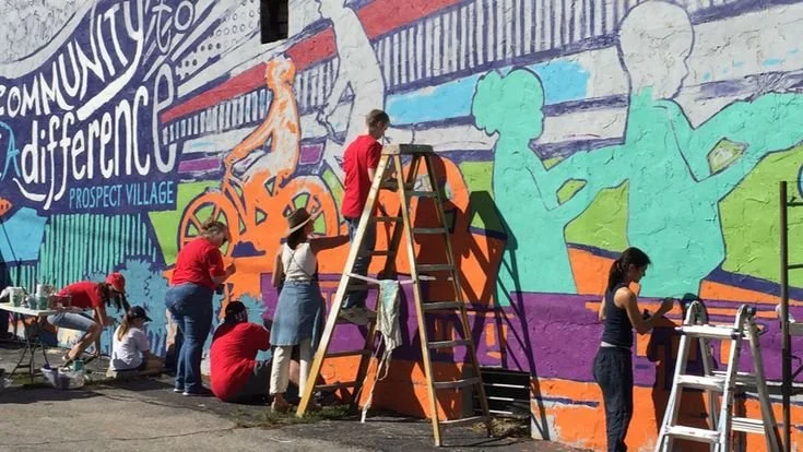 Artists painting a large public mural—creative placemaking and neighborhood activation.
