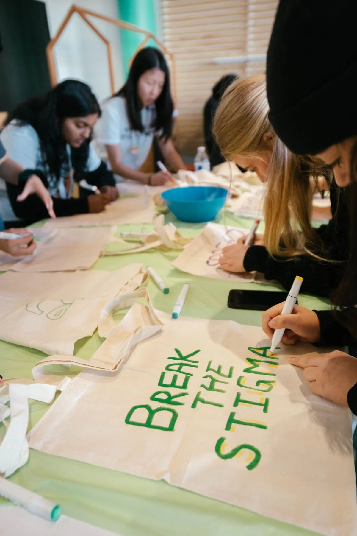 Group decorating tote bags that say “Break the Stigma”—mental health advocacy and community education.