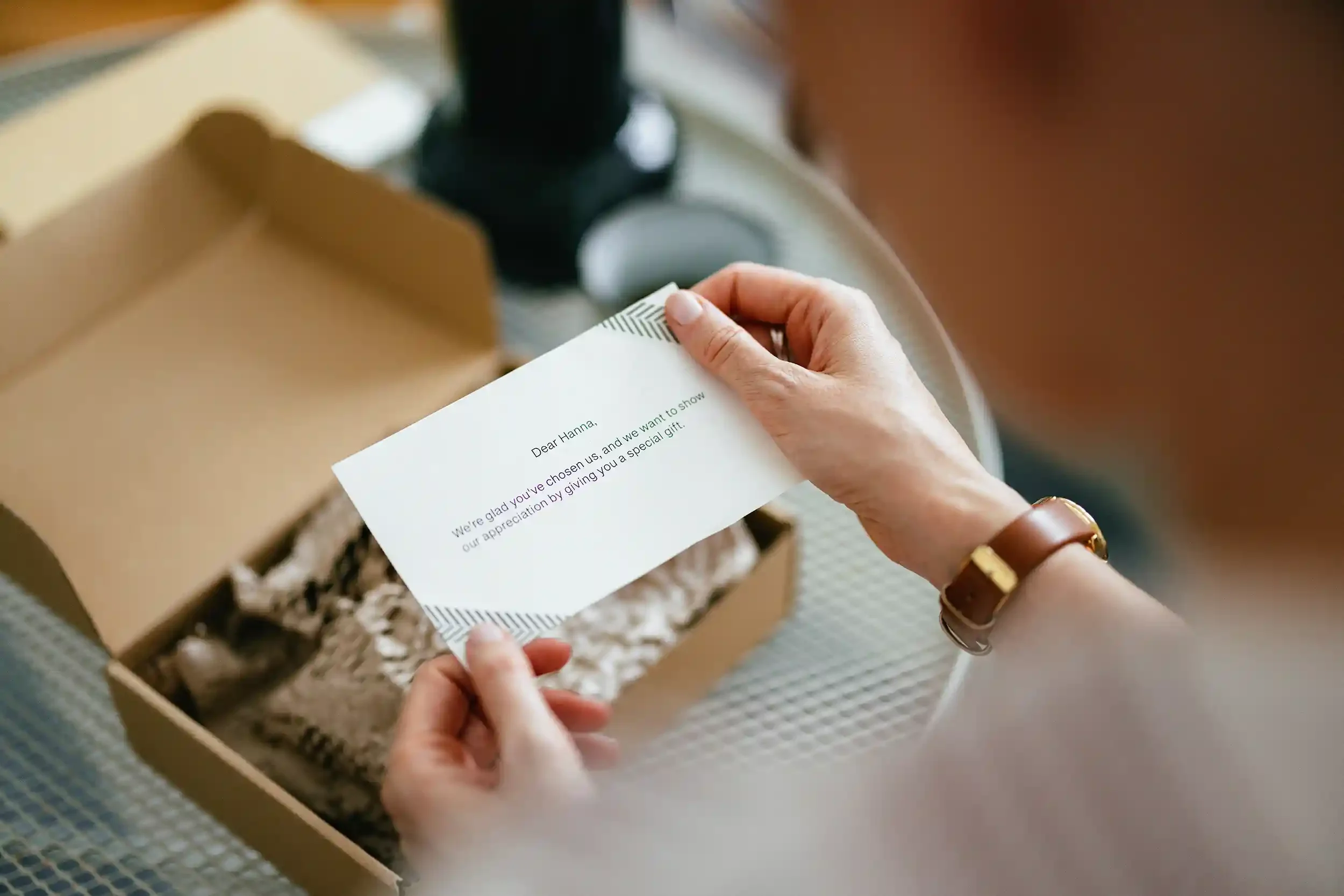An employee holds a note card from a cardboard box filled with gift wrapping paper