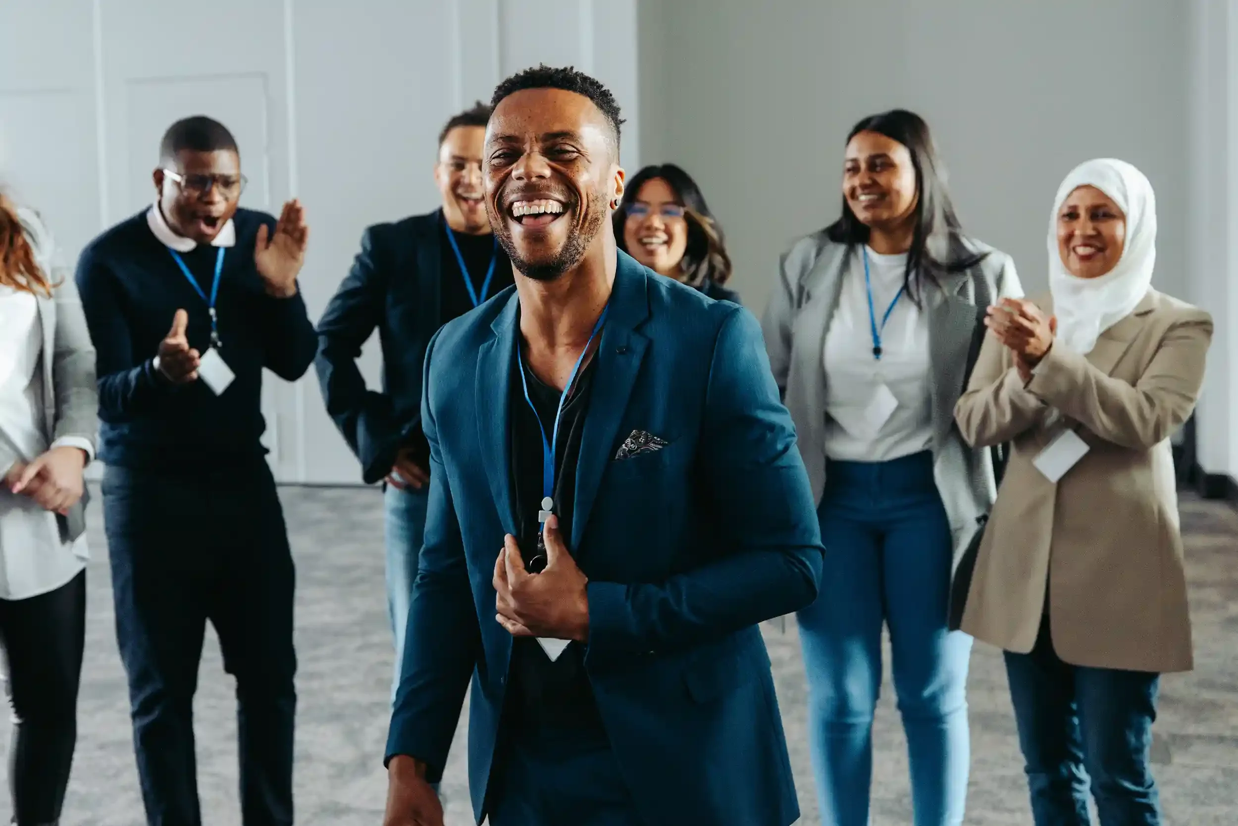 A group of people in business attire smiling and clapping during an conference event or team celebration