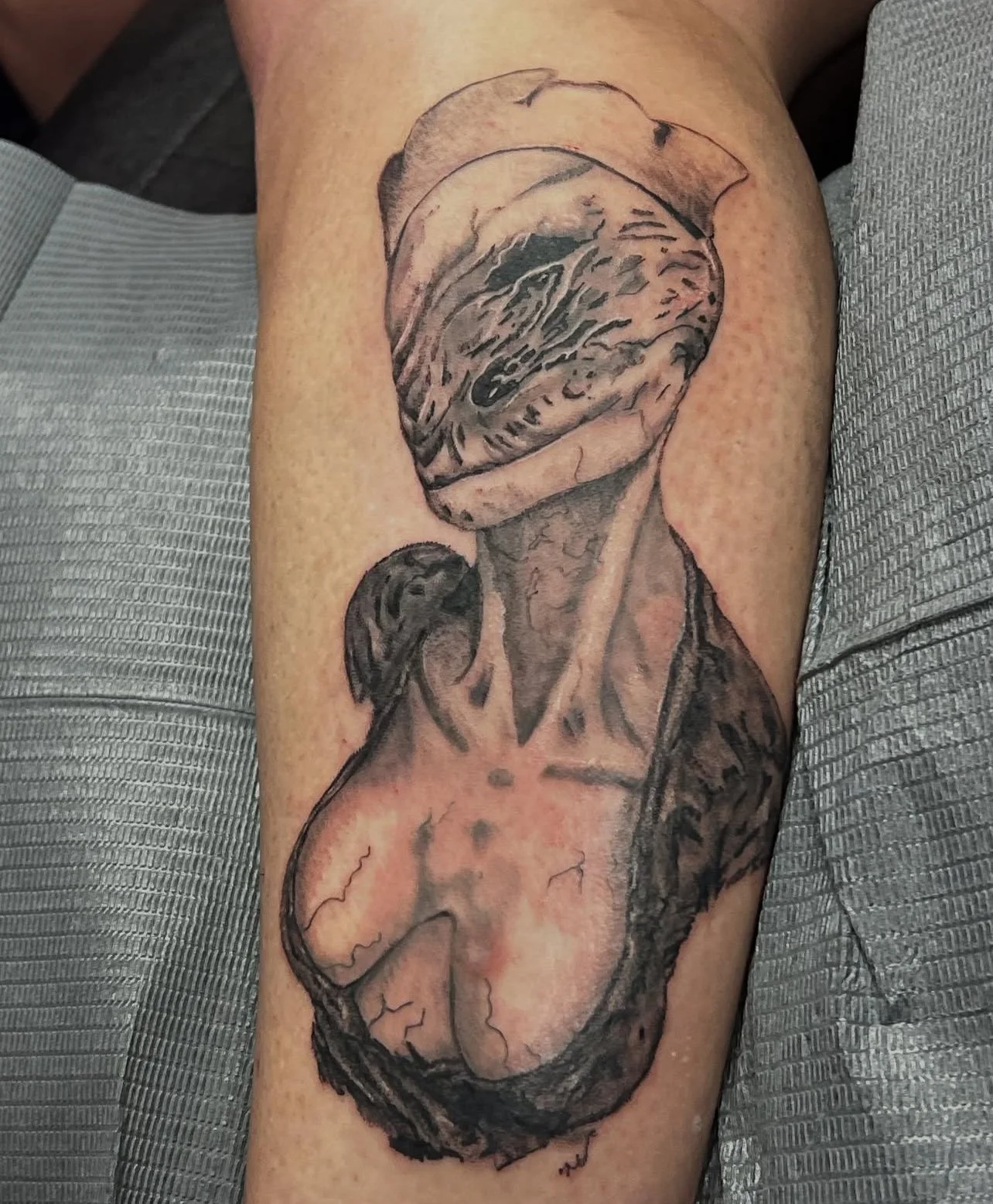 Black and gray tattoo of a human heart with intricate details on a person's arm.