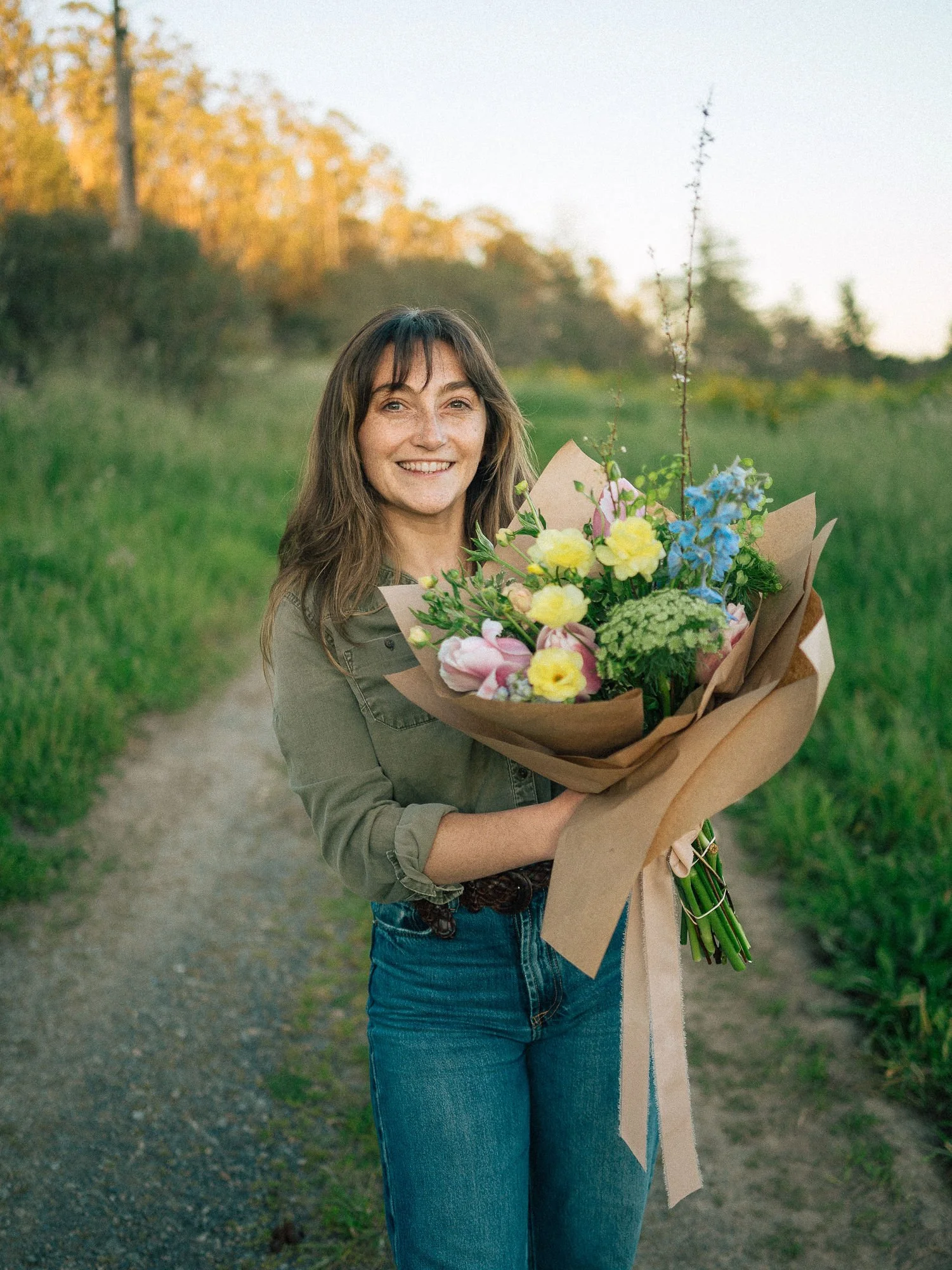 Lauren standing in a field holding a fresh, vibrant flower bouquet.
