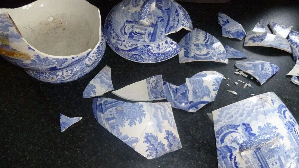 Broken blue and white porcelain vase and pieces on a black surface.