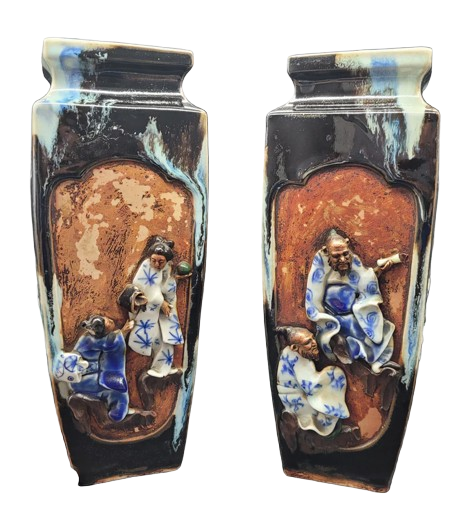 Two antique Chinese snuff bottles with intricate figures of children and cloud motifs, made of black and brown ceramic with blue and white painted designs.