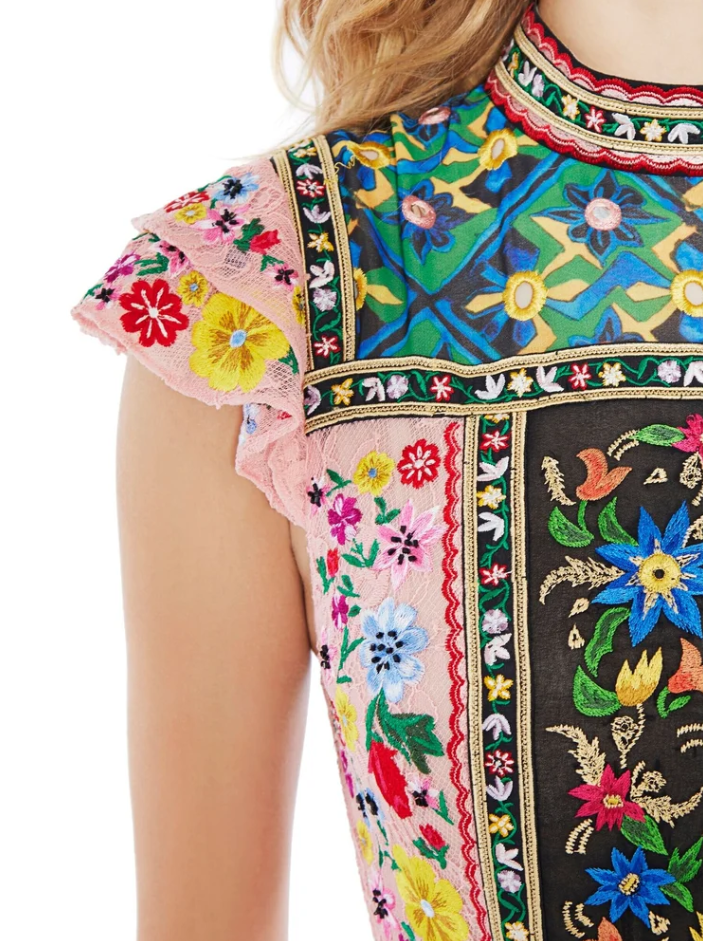 Close-up of a colorful embroidered top with floral patterns, ruffled pink sleeve, and intricate details.