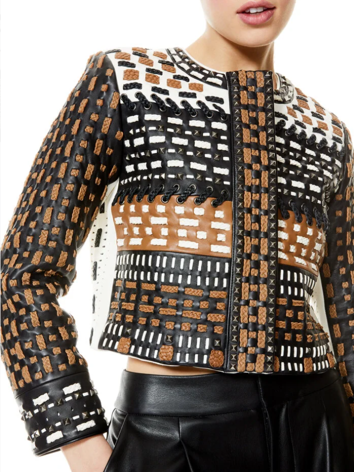 Close-up of a woman wearing a multicolored patterned leather jacket with black pants.
