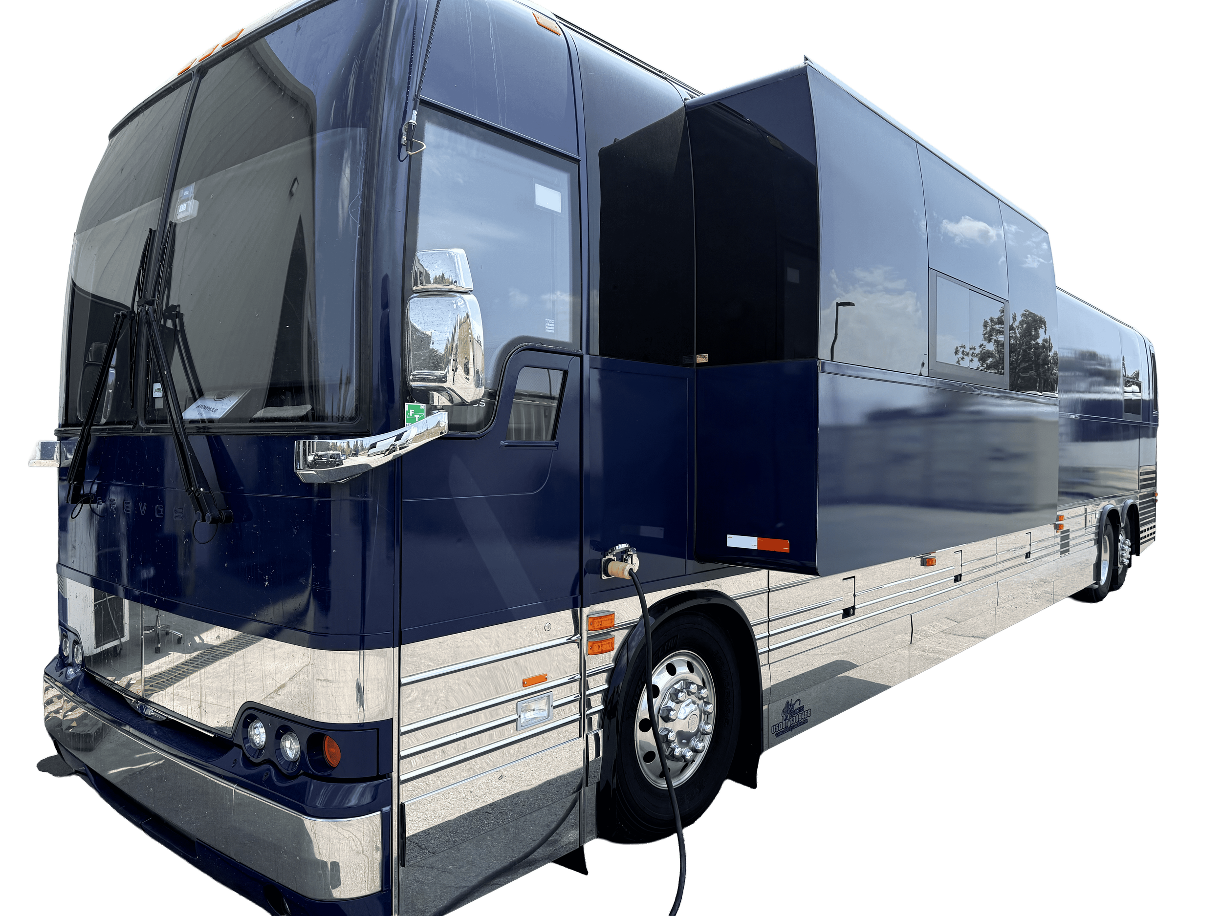 A large blue and silver tour bus with a chrome front bumper and multiple windows, parked outdoors on a paved surface, with a power cord plugged into the side.