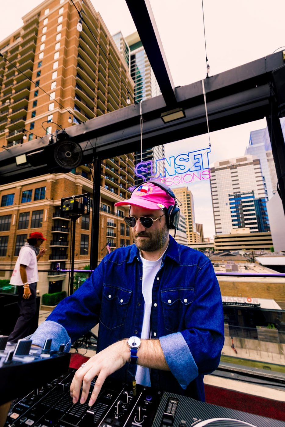 DJ spinning Sunset Sessions on Twins Rooftop with the downtown skyline