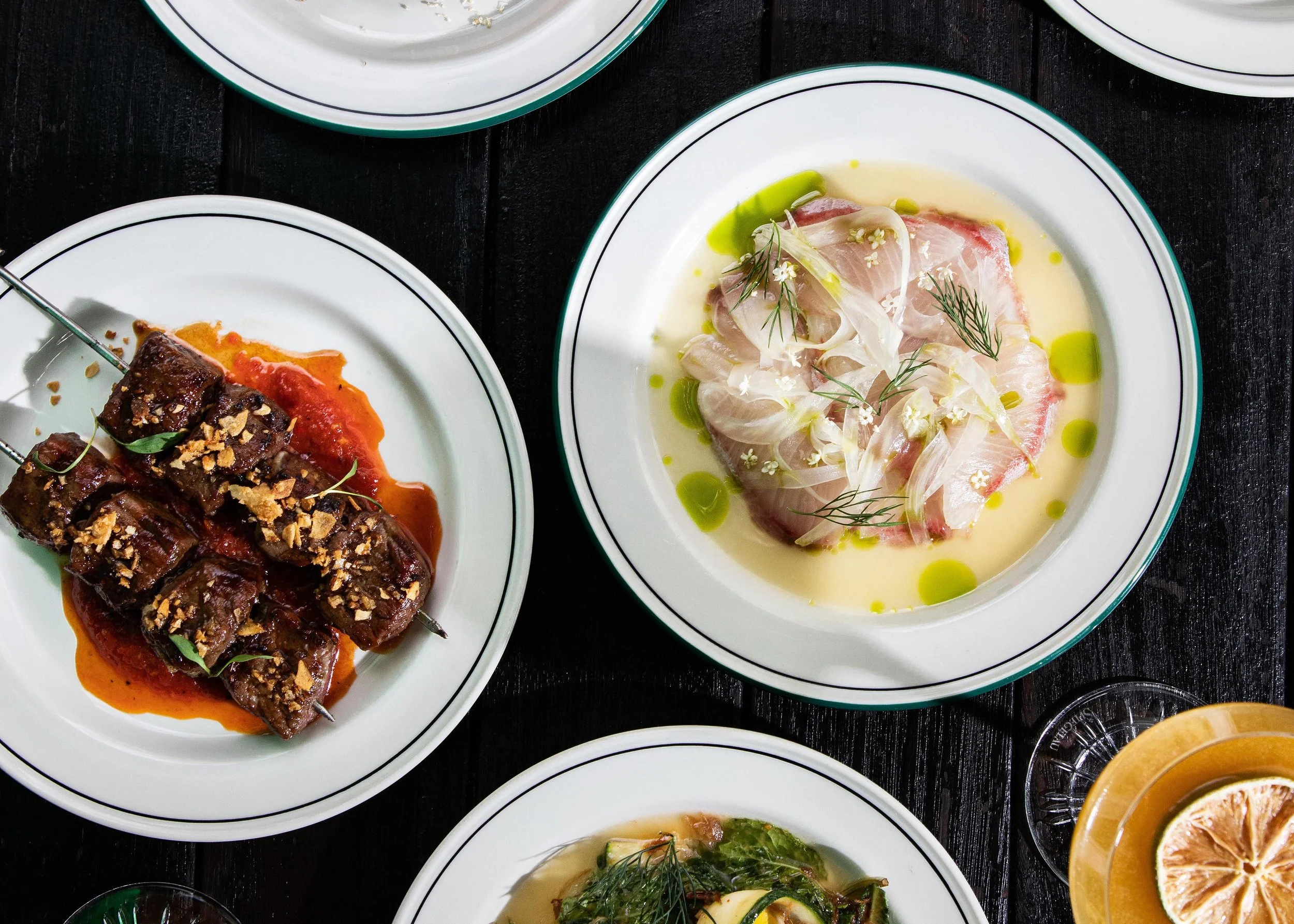 Various Longsong dishes served on white plates on a dark wooden table.